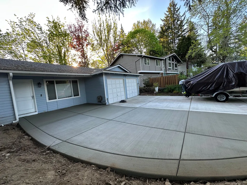 New broom finish concrete driveway with a curved edge and clean control joints in front of a two car garage