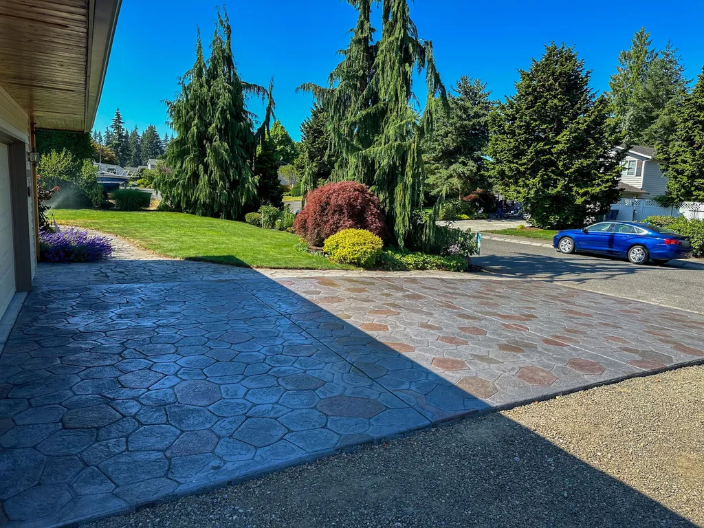 Stamped concrete driveway with a cobblestone pattern in gray and terracotta tones in front of a home garage